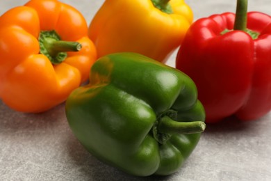 Photo of Fresh colorful bell peppers on gray textured table, closeup