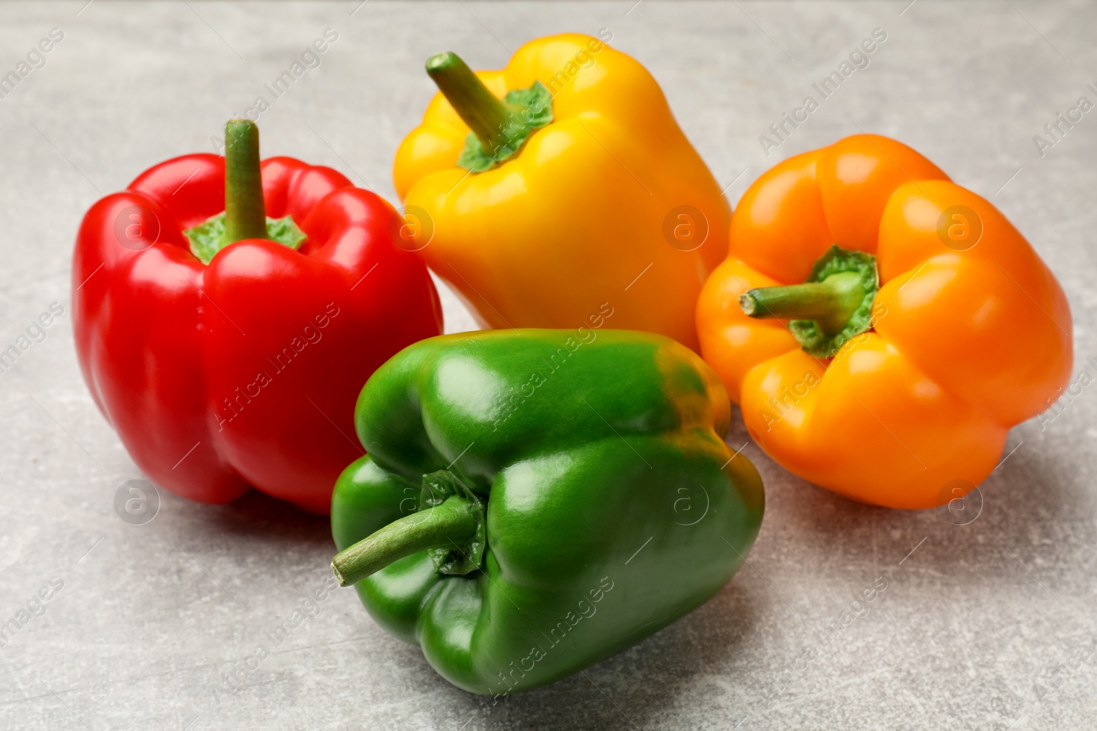 Photo of Fresh colorful bell peppers on gray textured table, closeup