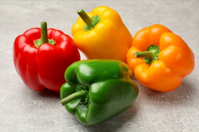 Photo of Fresh colorful bell peppers on gray textured table, closeup