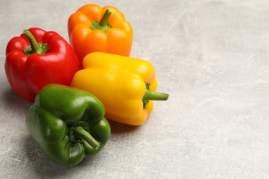 Photo of Fresh colorful bell peppers on gray textured table, closeup. Space for text