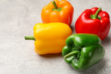 Photo of Fresh colorful bell peppers on gray textured table, closeup