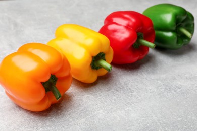 Photo of Fresh colorful bell peppers on gray textured table, closeup