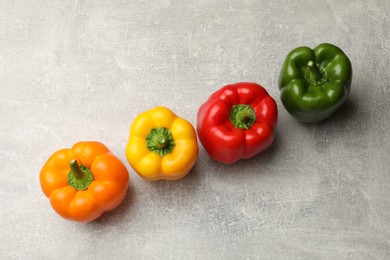 Photo of Fresh colorful bell peppers on gray textured table, flat lay