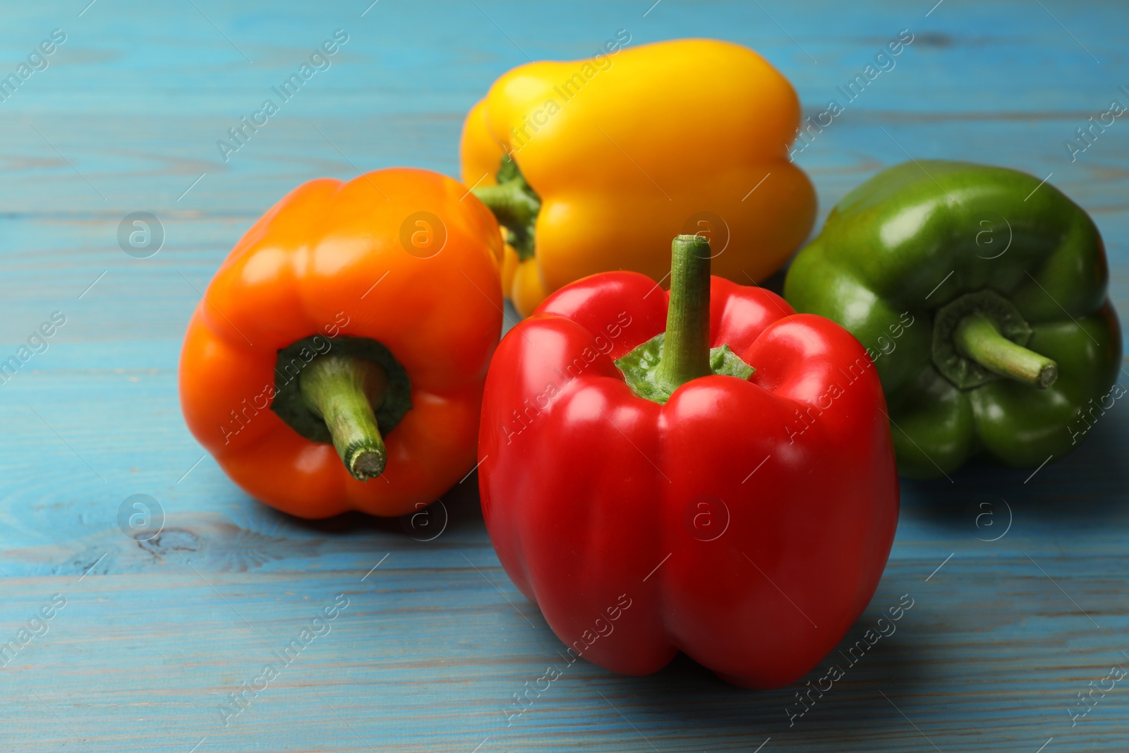 Fresh colorful bell peppers on blue wooden table, closeup Photo of Fresh colorful bell peppers on blue wooden table, closeup