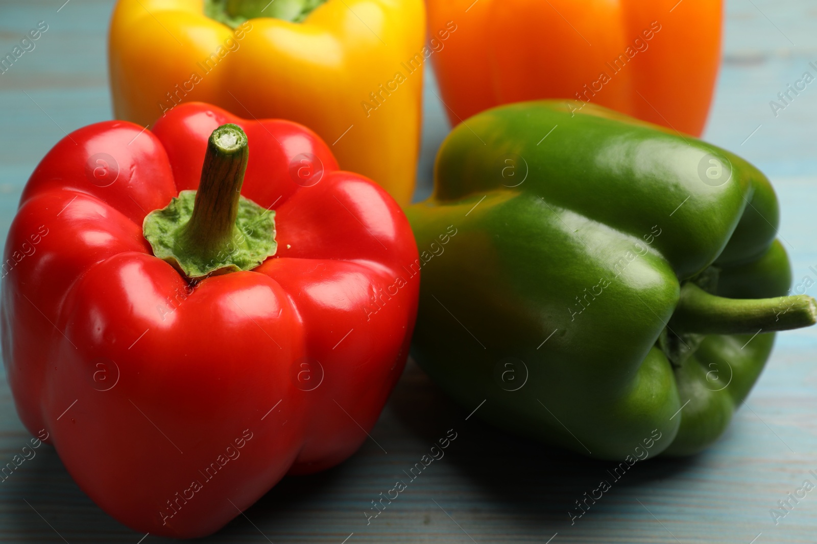 Fresh colorful bell peppers on blue wooden table, closeup Photo of Fresh colorful bell peppers on blue wooden table, closeup