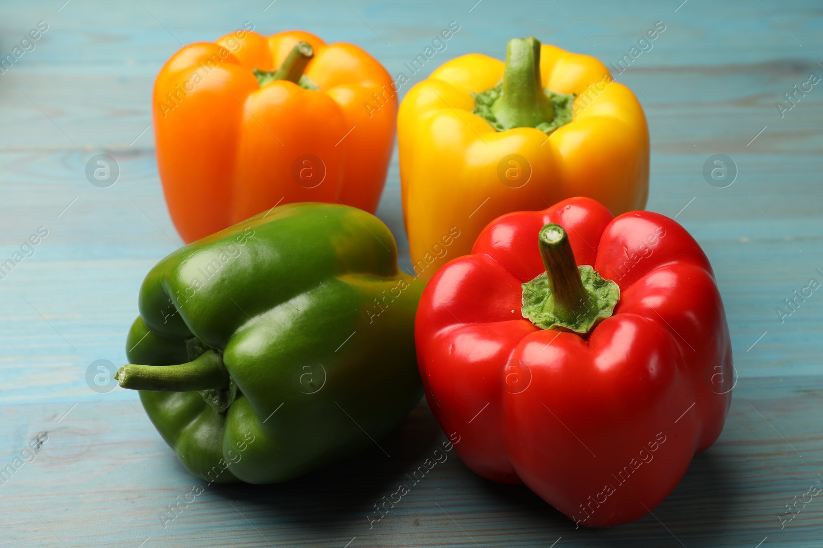 Fresh colorful bell peppers on blue wooden table, closeup Photo of Fresh colorful bell peppers on blue wooden table, closeup