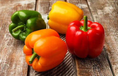 Photo of Fresh colorful bell peppers on wooden table, closeup