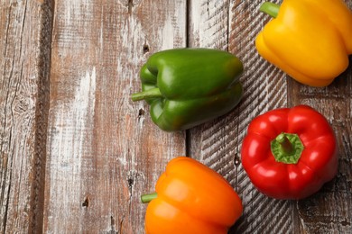 Photo of Fresh colorful bell peppers on wooden table, flat lay. Space for text