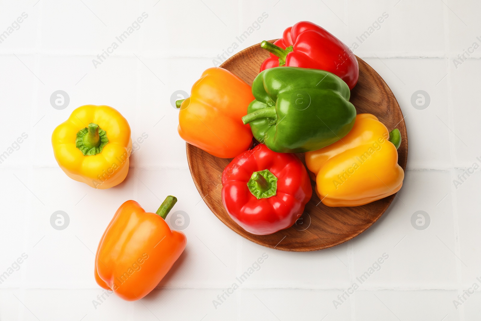 Fresh colorful bell peppers on white tiled table, flat lay Photo of Fresh colorful bell peppers on white tiled table, flat lay