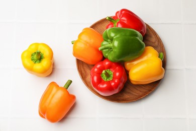 Photo of Fresh colorful bell peppers on white tiled table, flat lay