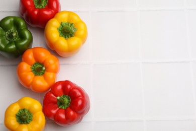 Photo of Fresh colorful bell peppers on white tiled table, flat lay. Space for text