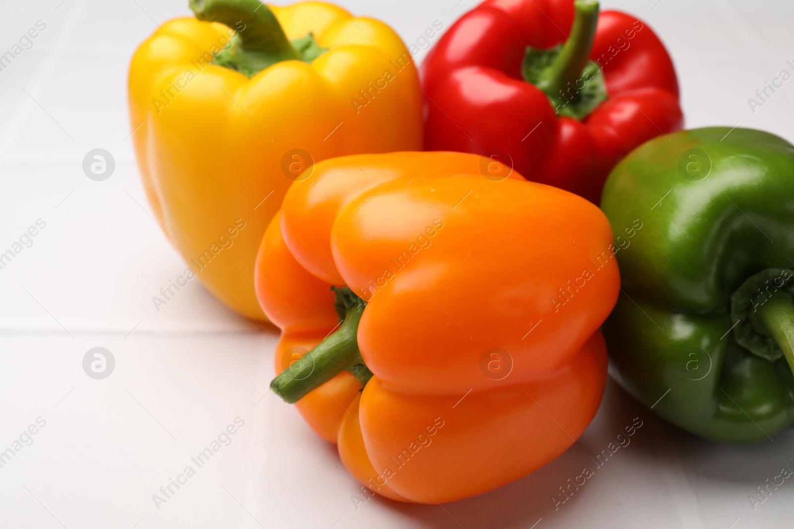 Photo of Fresh colorful bell peppers on white table, closeup