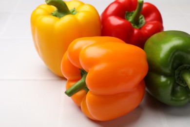 Photo of Fresh colorful bell peppers on white table, closeup