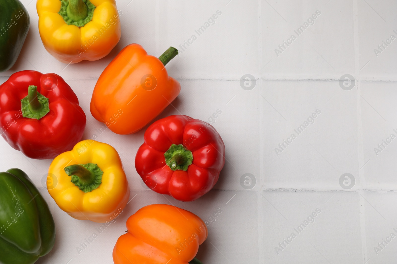 Fresh colorful bell peppers on white tiled table, flat lay. Space for text Photo of Fresh colorful bell peppers on white tiled table, flat lay. Space for text