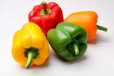 Photo of Fresh colorful bell peppers on white table, closeup