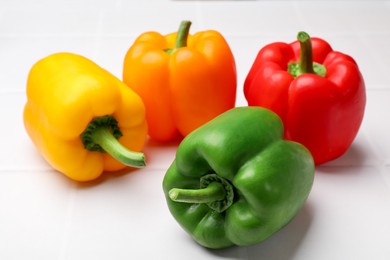 Photo of Fresh colorful bell peppers on white table, closeup