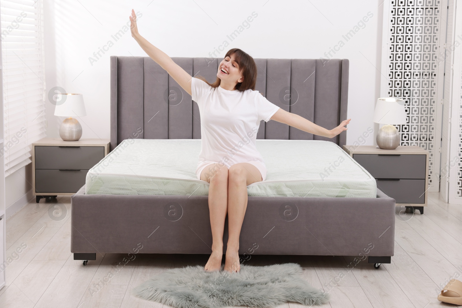 Smiling woman stretching on bed at home Photo of Smiling woman stretching on bed at home