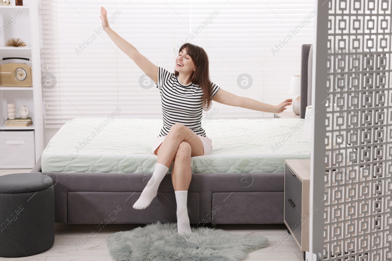 Smiling woman stretching on bed at home Photo of Smiling woman stretching on bed at home