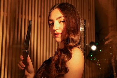 Photo of Woman curling her beautiful hair in dressing room