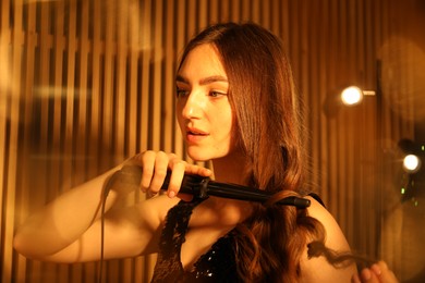 Photo of Woman curling her beautiful hair in dressing room