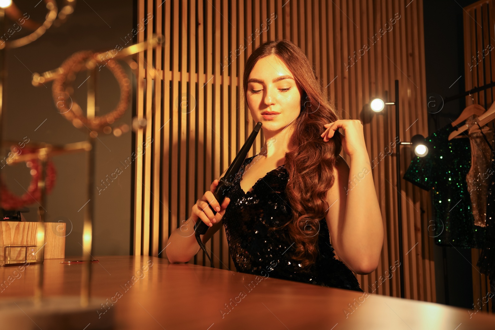 Woman curling her beautiful hair in dressing room Photo of Woman curling her beautiful hair in dressing room