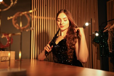 Photo of Woman curling her beautiful hair in dressing room