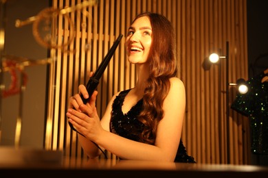 Photo of Woman curling her beautiful hair in dressing room