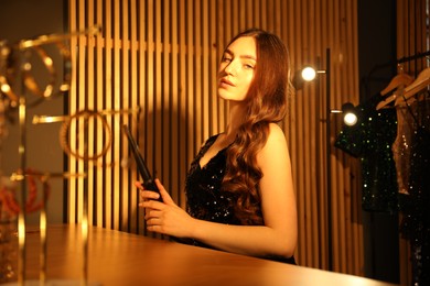 Photo of Woman curling her beautiful hair in dressing room