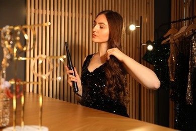 Photo of Woman curling her beautiful hair in dressing room