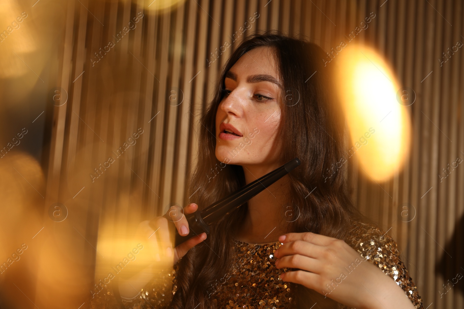 Woman curling her beautiful hair in dressing room Photo of Woman curling her beautiful hair in dressing room