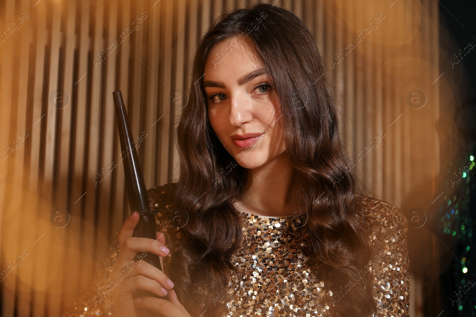 Woman curling her beautiful hair in dressing room Photo of Woman curling her beautiful hair in dressing room