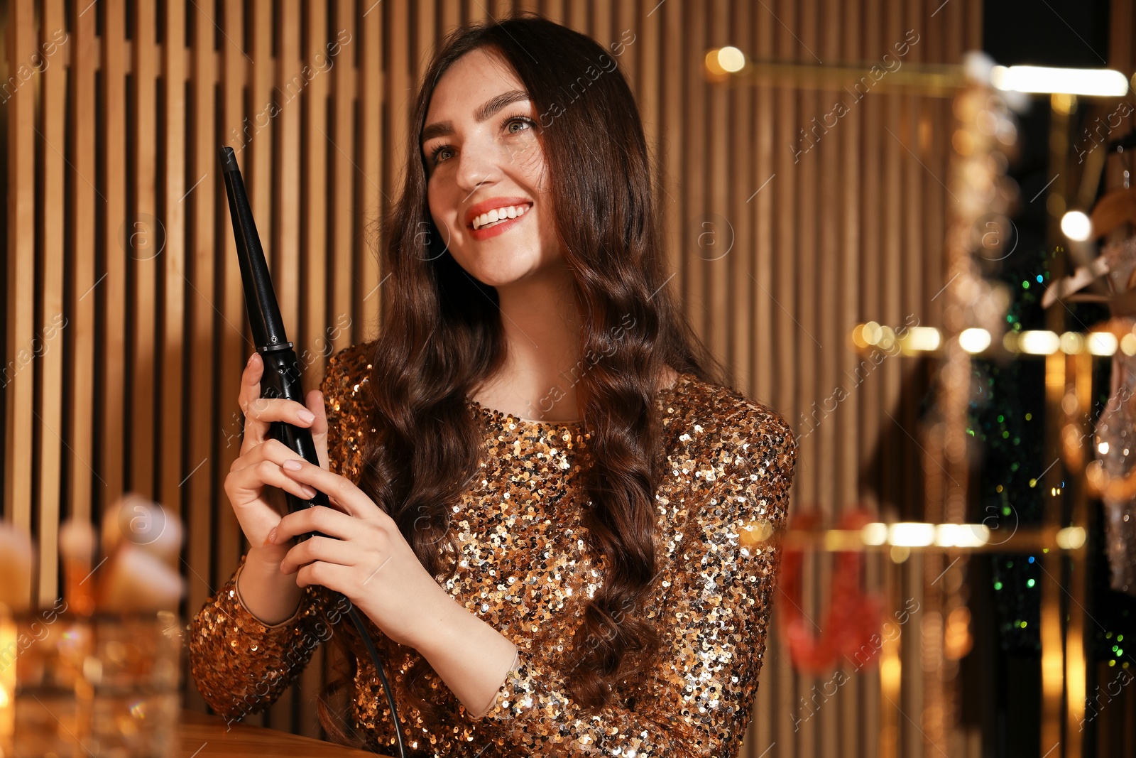 Woman curling her beautiful hair in dressing room Photo of Woman curling her beautiful hair in dressing room
