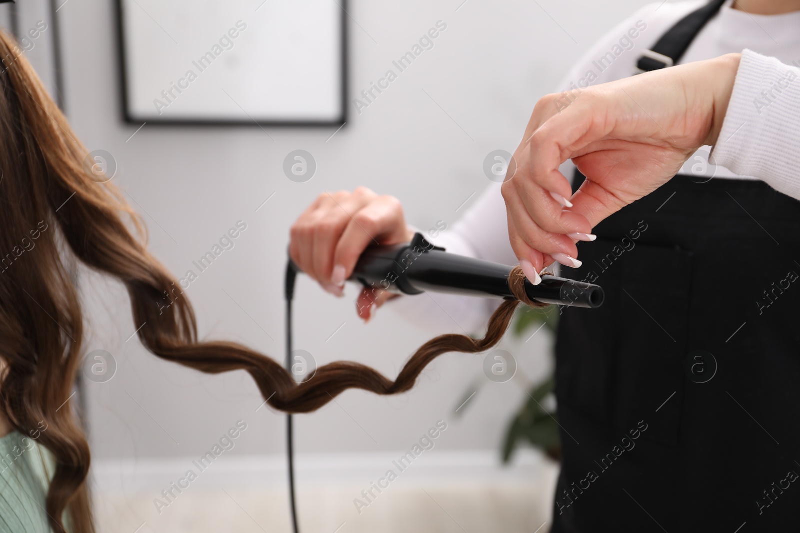 Hairdresser curling woman's hair in salon, closeup Photo of Hairdresser curling woman's hair in salon, closeup
