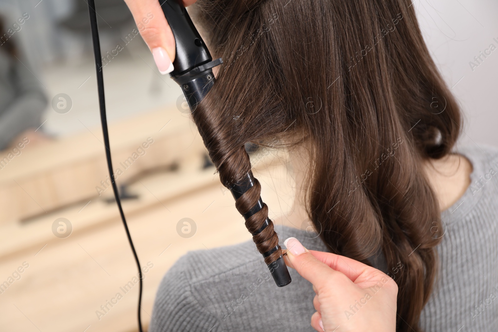 Hairdresser curling woman's hair in salon, closeup Photo of Hairdresser curling woman's hair in salon, closeup