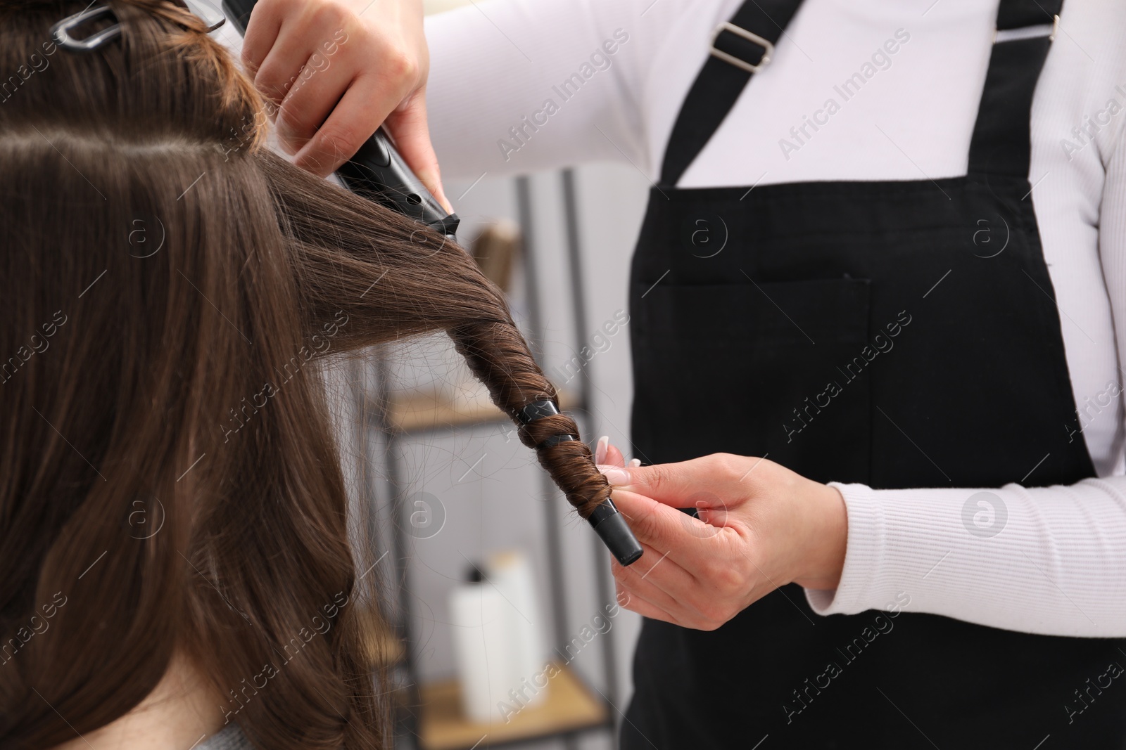 Hairdresser curling woman's hair in salon, closeup Photo of Hairdresser curling woman's hair in salon, closeup