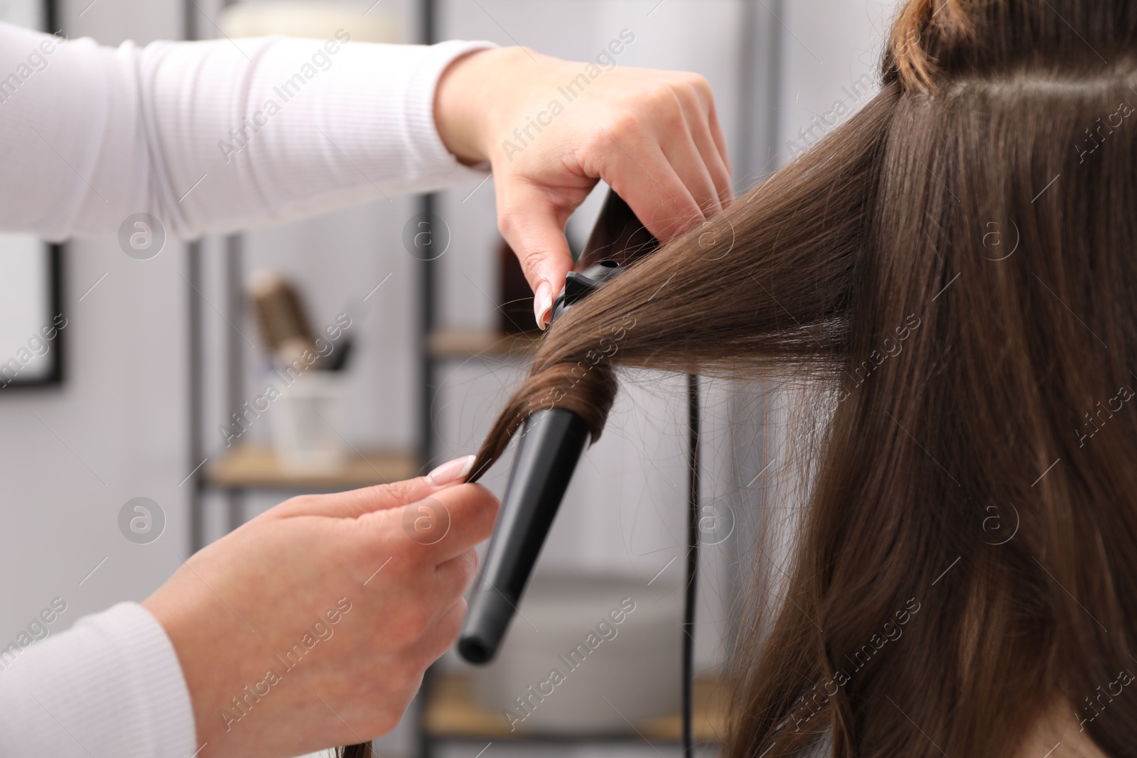 Hairdresser curling woman's hair in salon, closeup Photo of Hairdresser curling woman's hair in salon, closeup