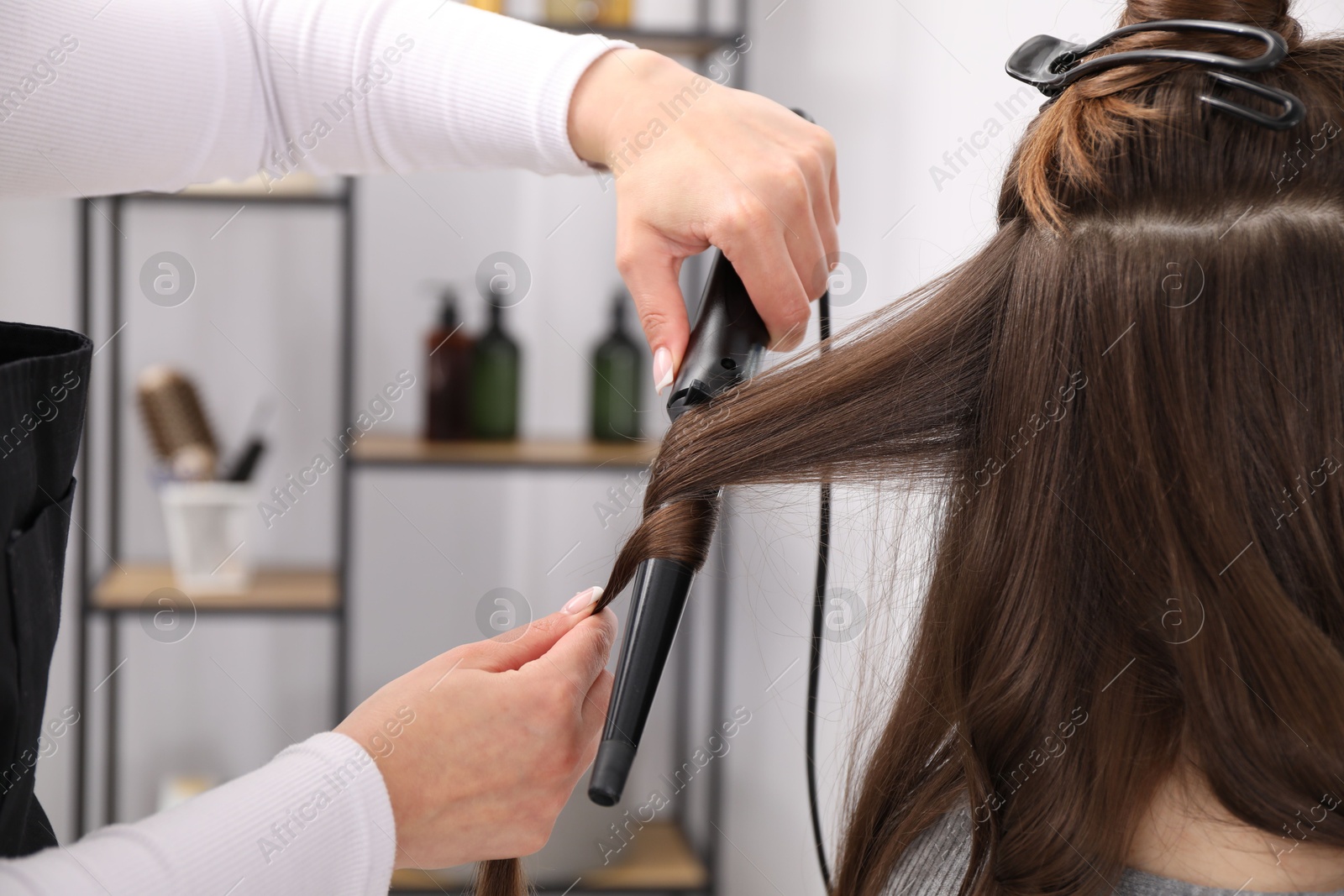 Hairdresser curling woman's hair in salon, closeup Photo of Hairdresser curling woman's hair in salon, closeup