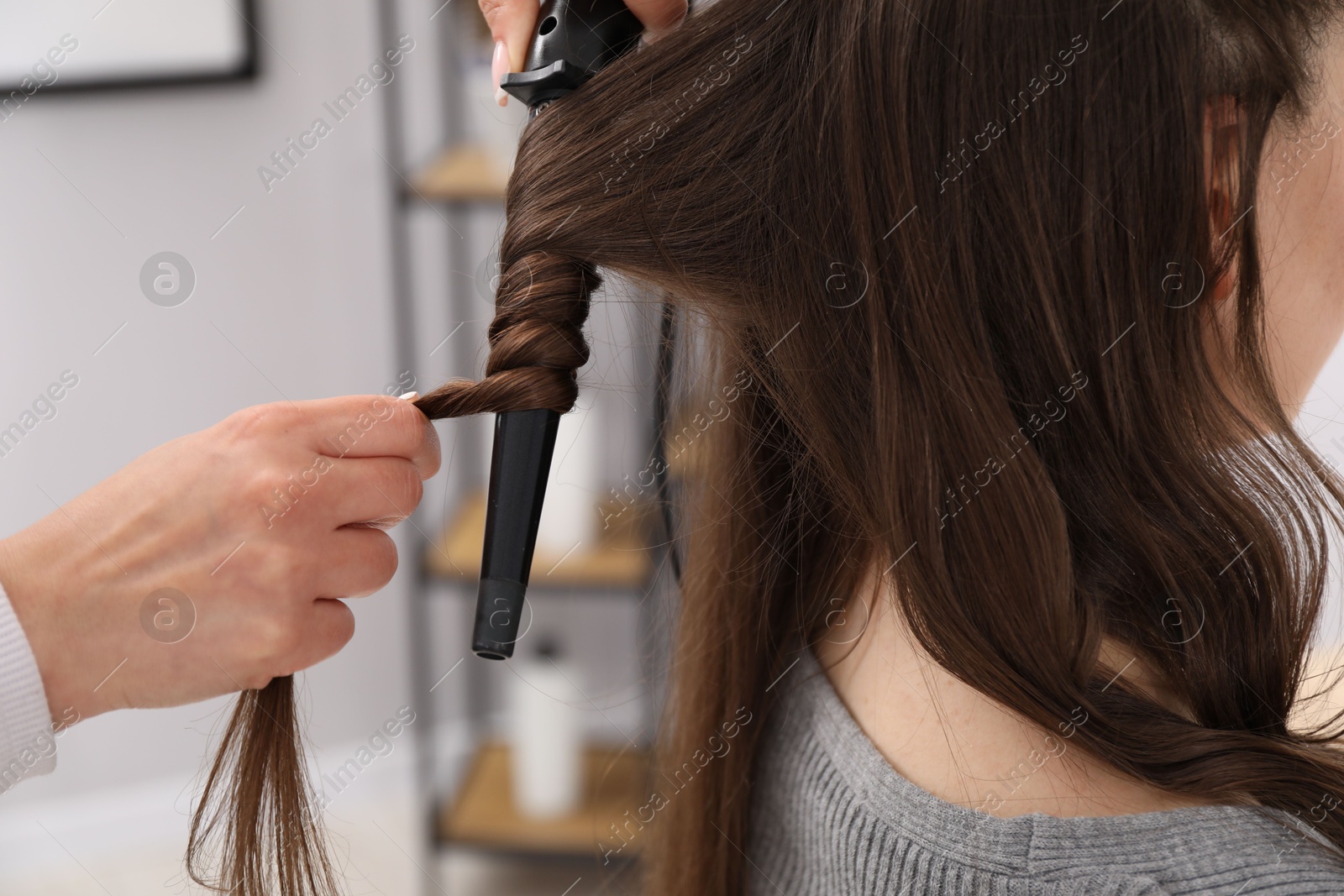 Hairdresser curling woman's hair in salon, closeup Photo of Hairdresser curling woman's hair in salon, closeup