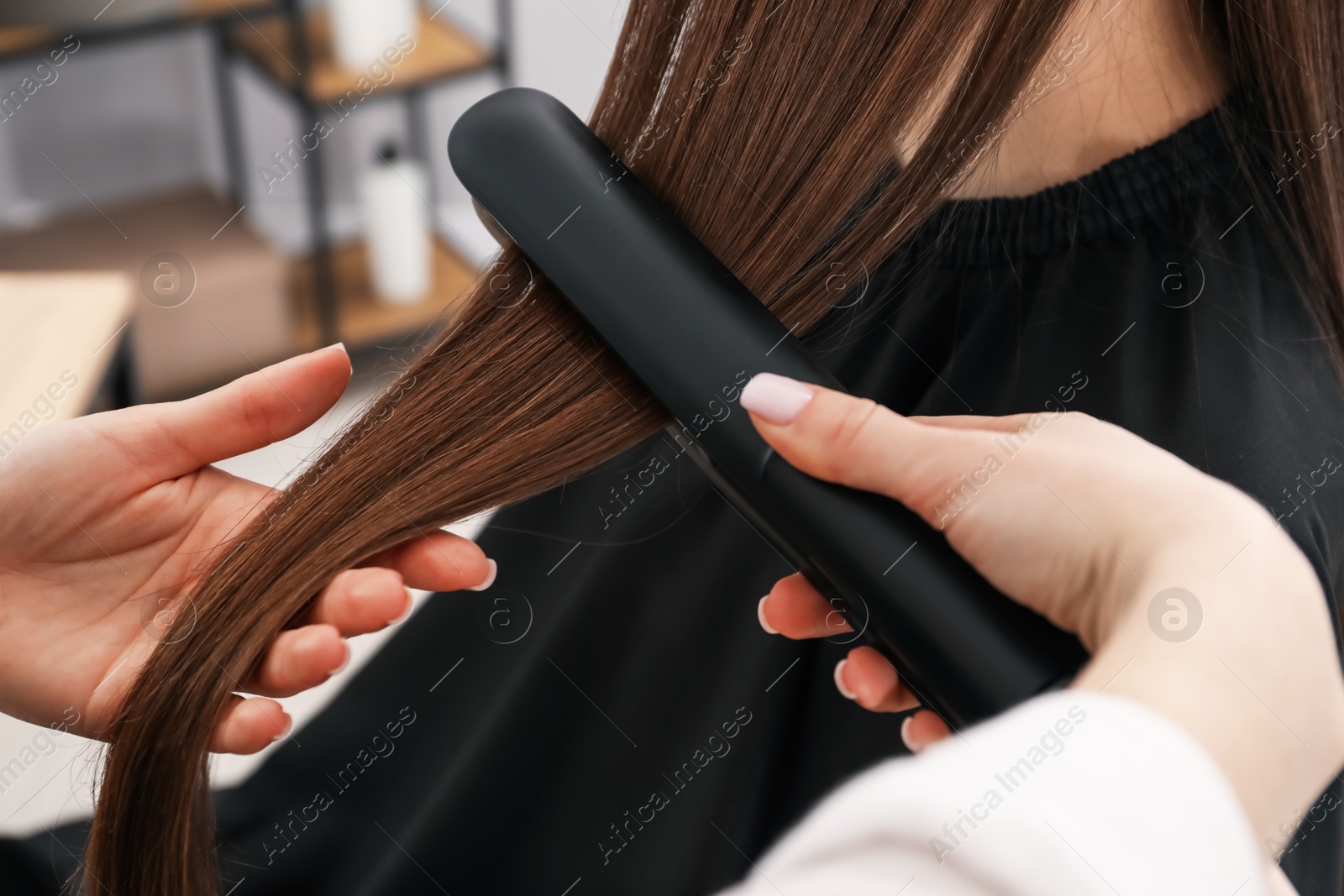 Hairdresser straightening woman's hair in salon, closeup Photo of Hairdresser straightening woman's hair in salon, closeup
