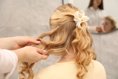 Photo of Hairdresser styling woman's hair in salon, closeup