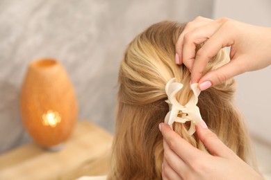Photo of Hairdresser styling woman's hair in salon, closeup