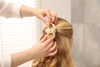 Photo of Hairdresser styling woman's hair in salon, closeup
