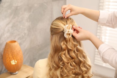 Photo of Hairdresser styling woman's hair in salon, closeup. Space for text