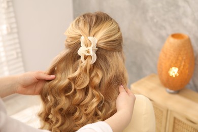 Photo of Hairdresser styling woman's hair in salon, closeup