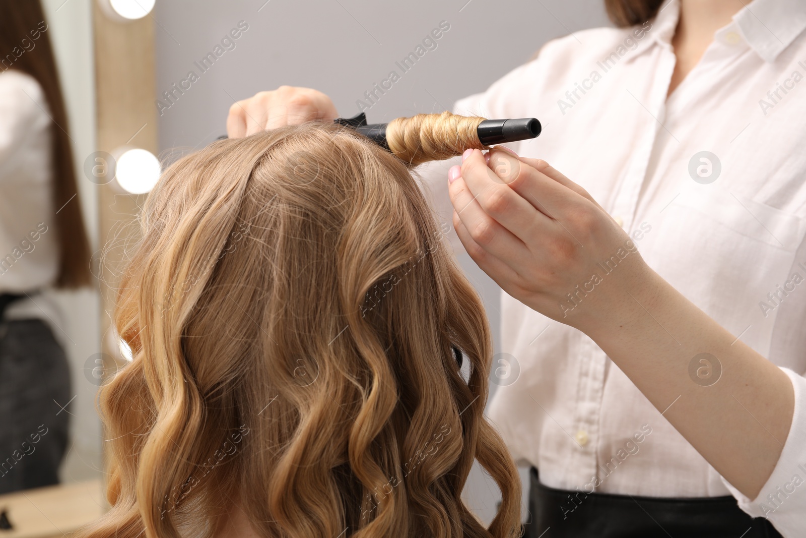 Hairdresser curling woman's hair in salon, closeup Photo of Hairdresser curling woman's hair in salon, closeup