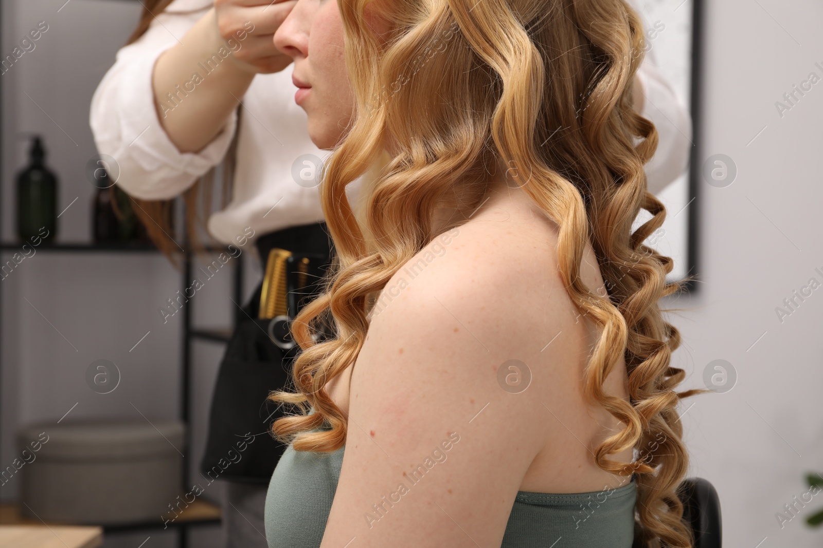 Hairdresser curling woman's hair in salon, closeup Photo of Hairdresser curling woman's hair in salon, closeup