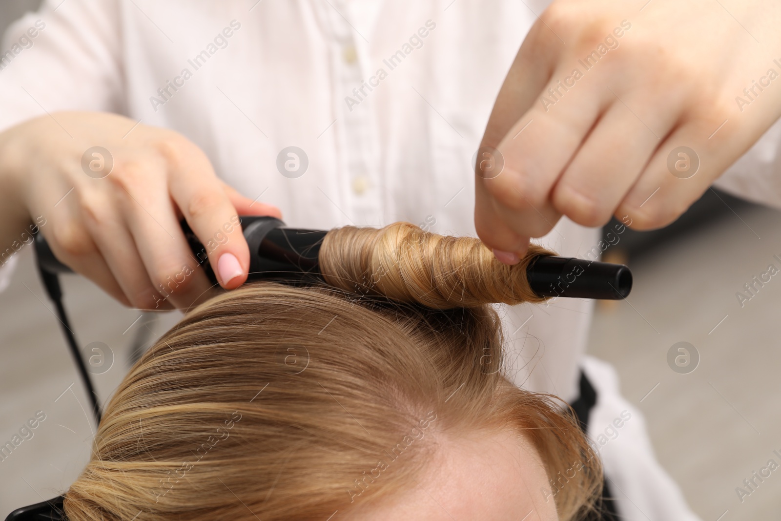 Hairdresser curling woman's hair in salon, closeup Photo of Hairdresser curling woman's hair in salon, closeup