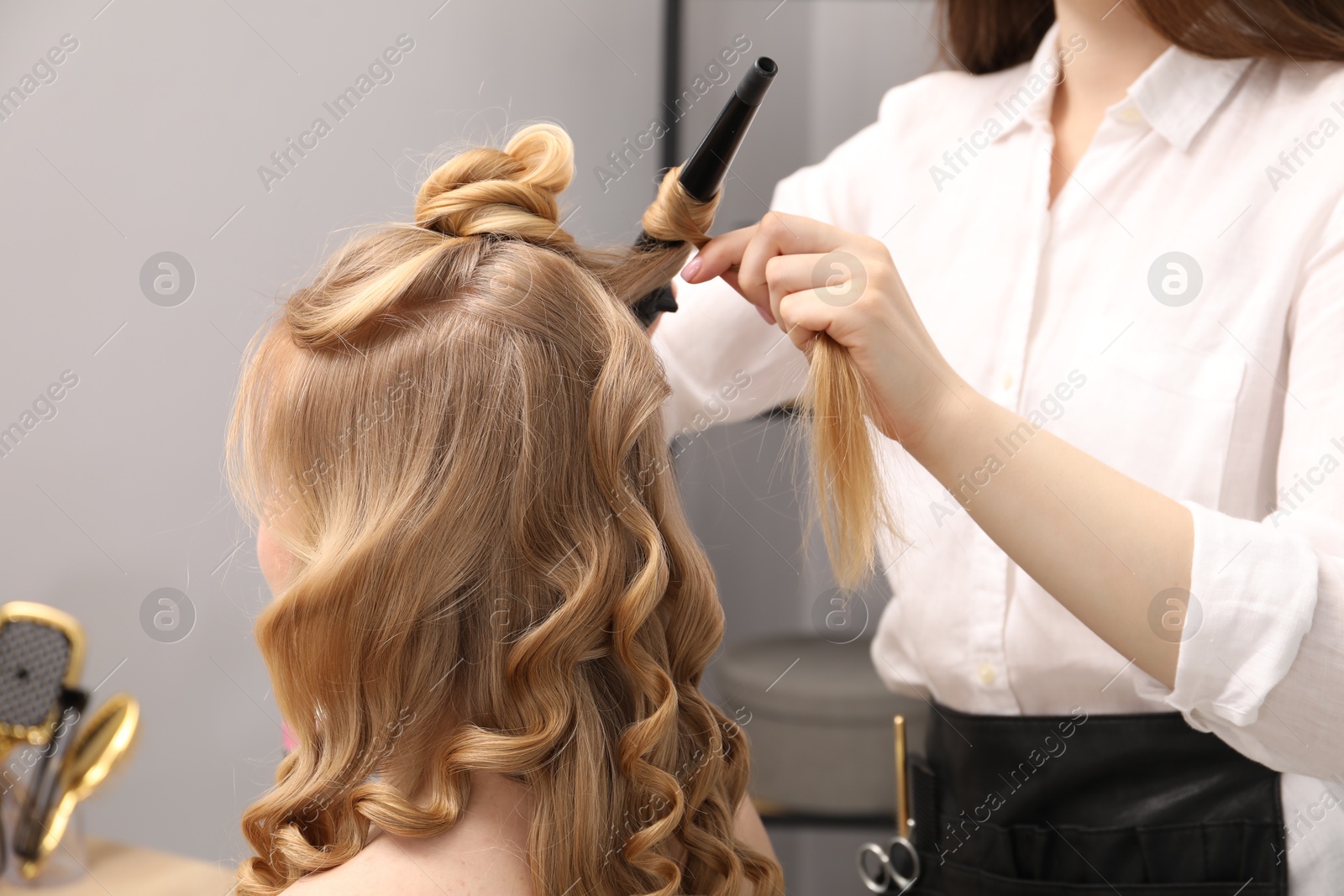 Hairdresser curling woman's hair in salon, closeup Photo of Hairdresser curling woman's hair in salon, closeup