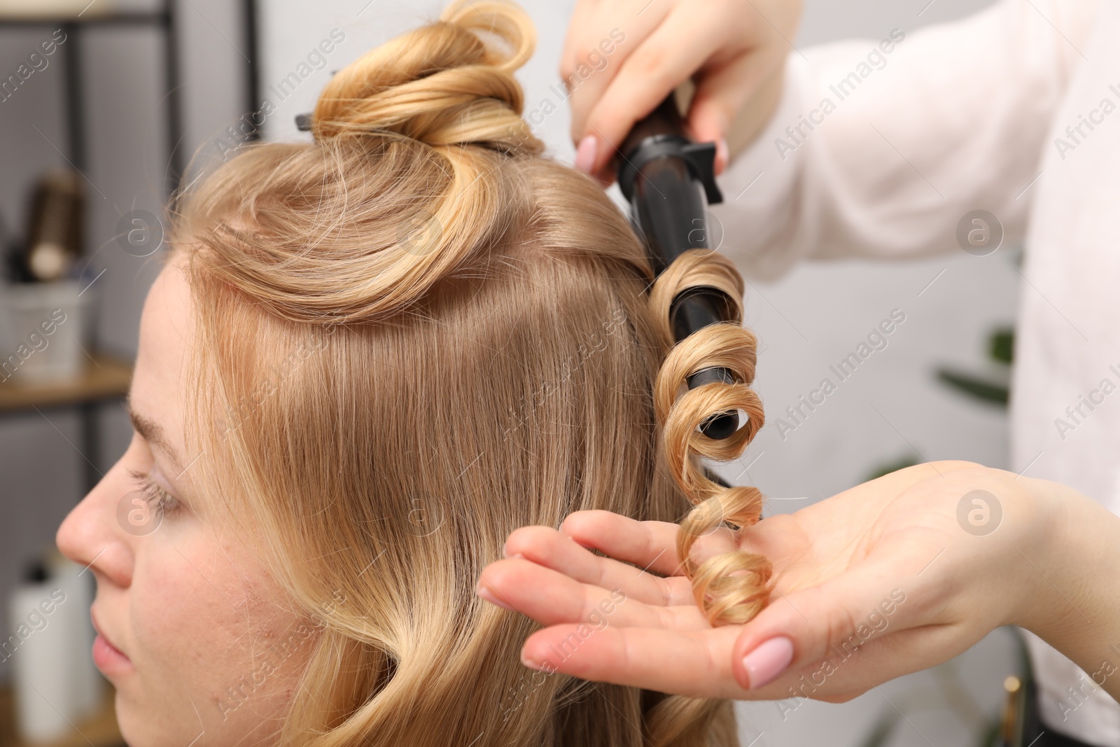 Hairdresser curling woman's hair in salon, closeup Photo of Hairdresser curling woman's hair in salon, closeup
