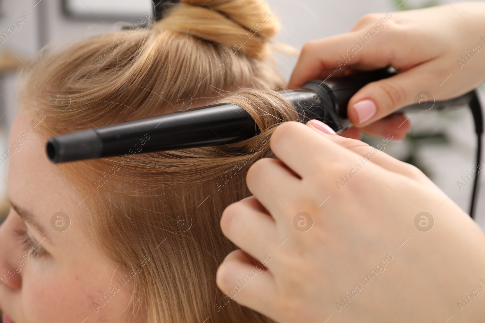 Hairdresser curling woman's hair in salon, closeup Photo of Hairdresser curling woman's hair in salon, closeup